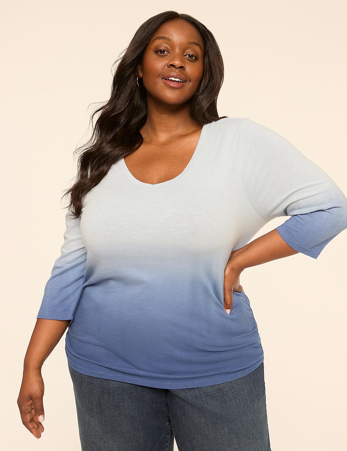 A woman with dark hair and a warm smile poses in a light blue and white ombre top and jeans against a plain, light-colored background. Product Image 1