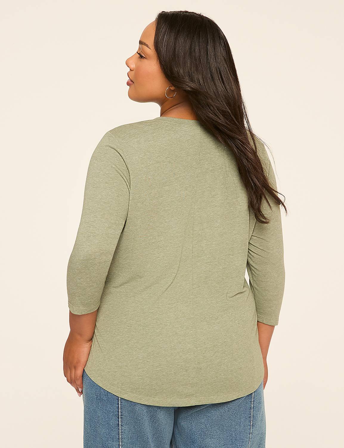 A woman in a green shirt and blue jeans stands against a plain beige background. Product Image 2