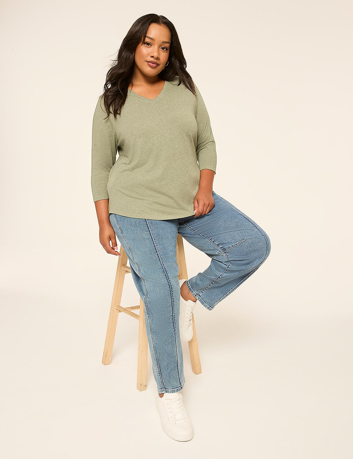 A woman in a green top and jeans sits on a stool against a plain white background. Product Image 3