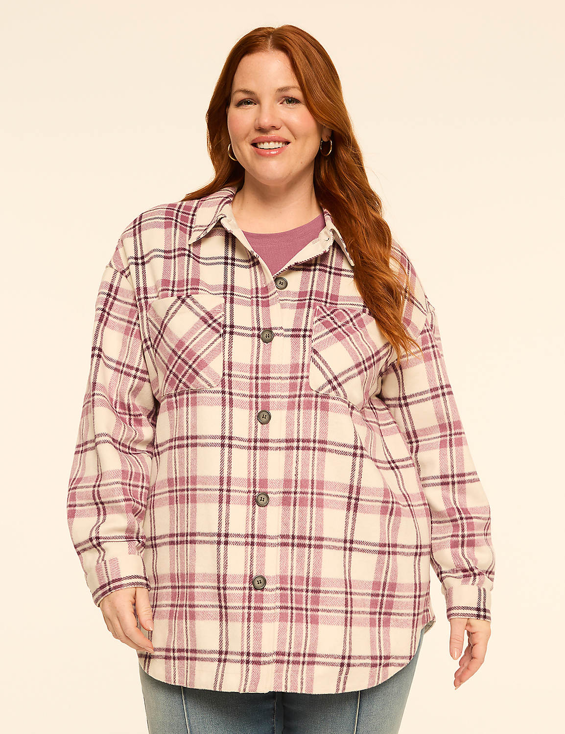 A smiling woman with red hair stands in the foreground wearing a plaid shirt over a purple top, against a plain, light-colored background. Product Image 1