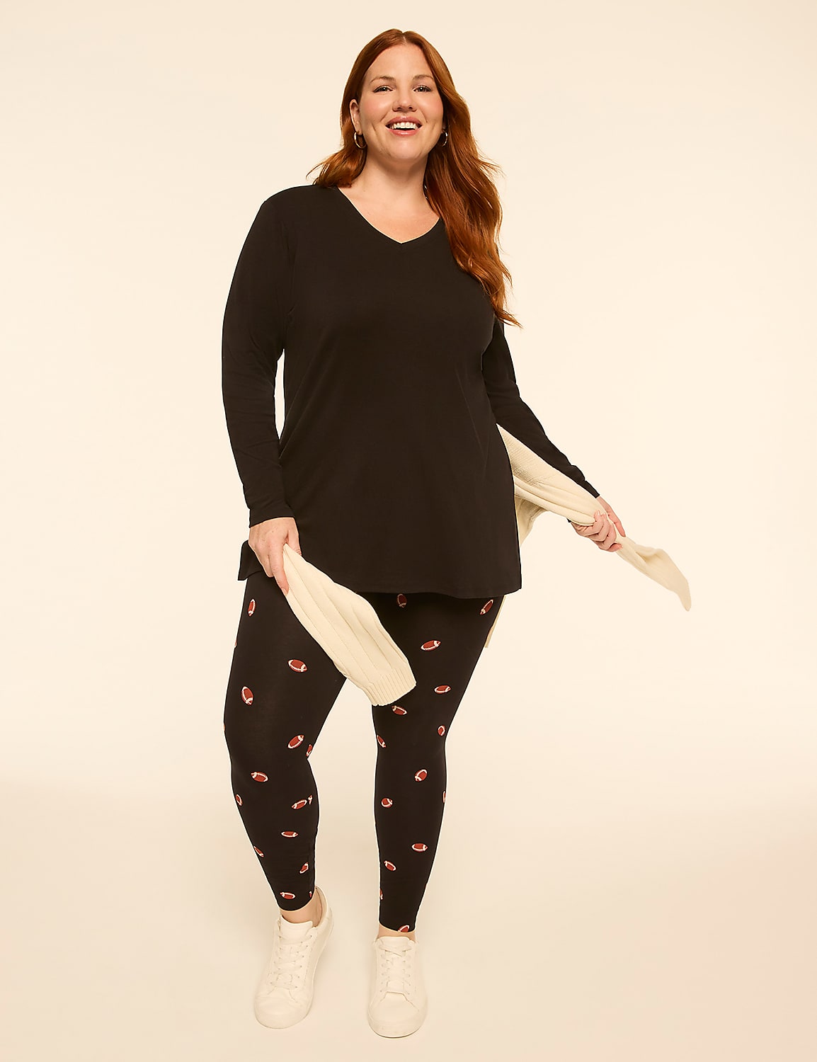 A smiling woman in a black v-neck top and patterned leggings stands against a plain, light-colored background. Product Image 3