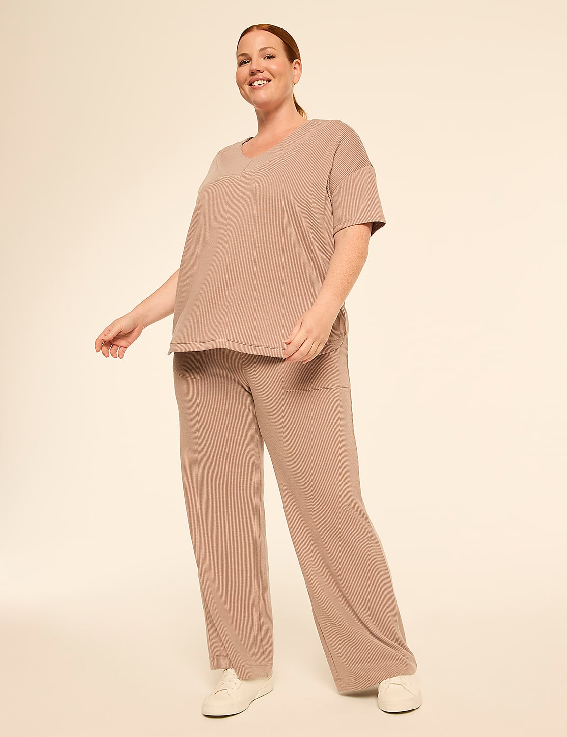 A smiling woman in a beige ribbed loungewear set stands against a plain, light beige background. Product Image 3
