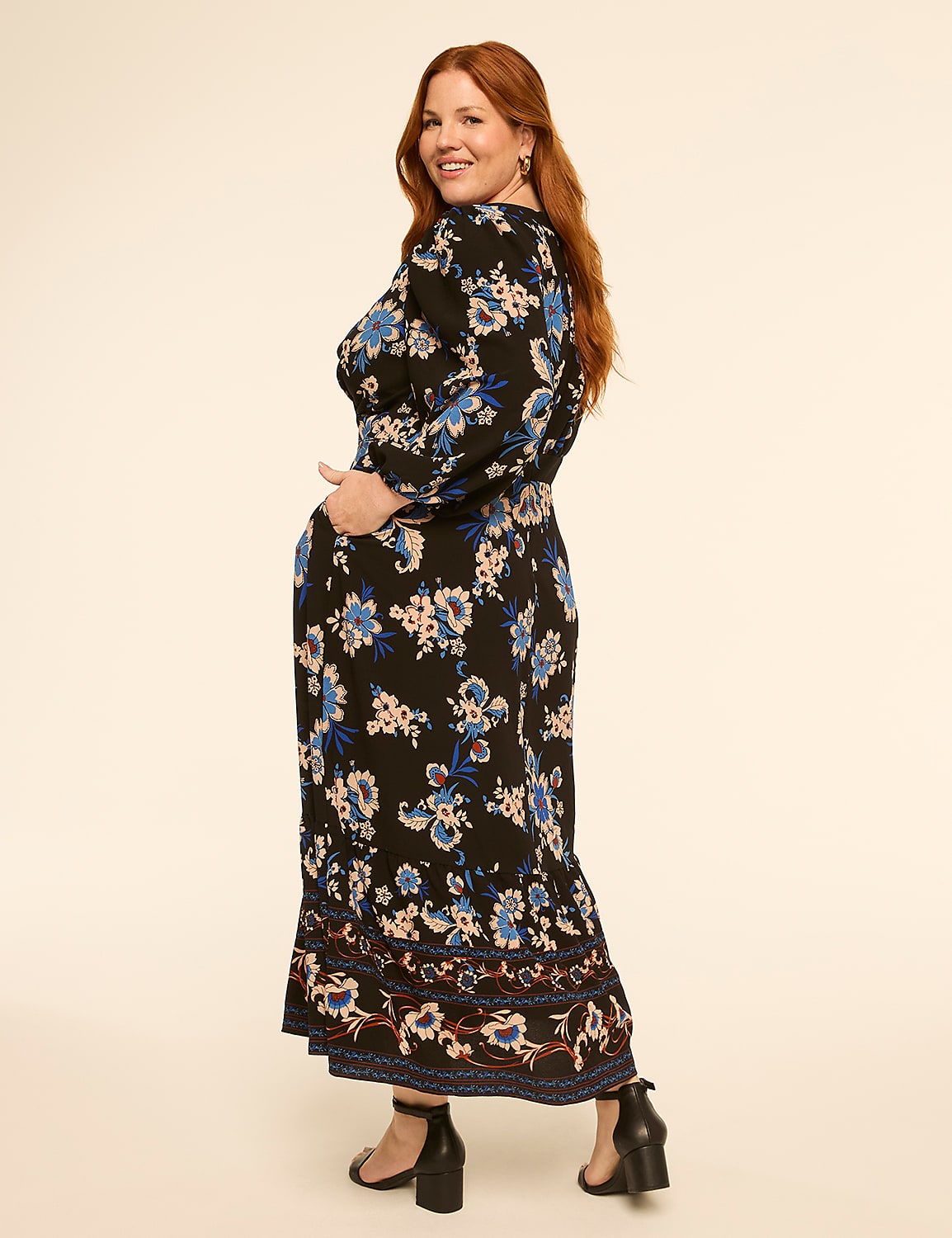 A woman with red hair in a floral dress stands with her hand in her pocket against a plain, light-colored background. Product Image 2