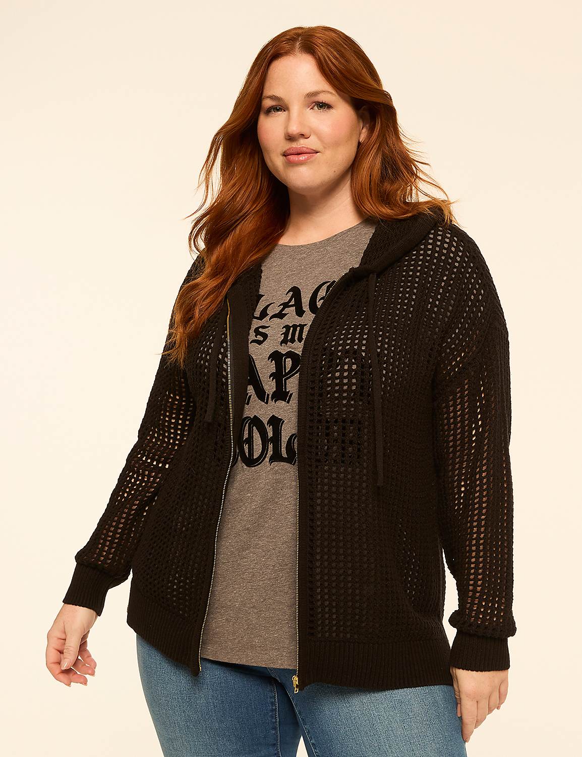 A woman with red hair stands in the foreground wearing a black hooded cardigan over a graphic t-shirt and jeans, against a plain, light-colored background. Product Image 1