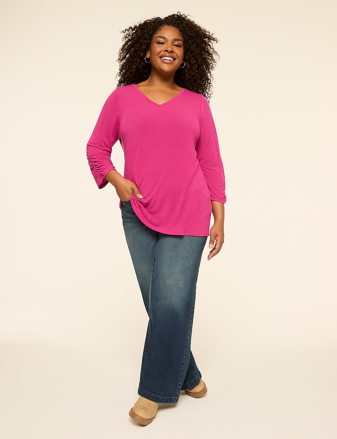 A smiling woman in a pink top and blue jeans stands against a plain, light background. Product Image 3