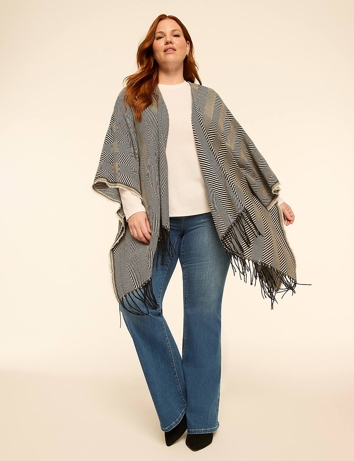 A woman in a patterned poncho and jeans stands against a plain, light-colored background. Product Image 1