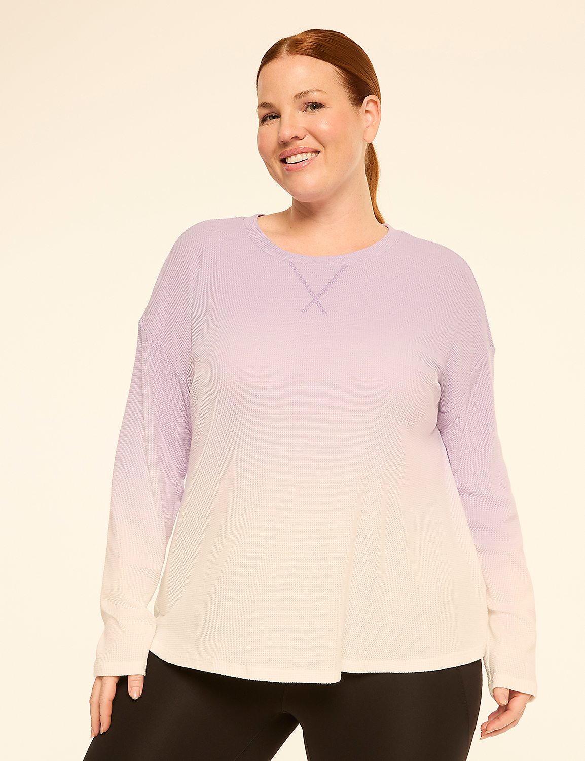 A smiling woman with red hair pulled back in a ponytail wears a long-sleeved, ombre purple and white top and black leggings against a plain, light-colored background. Product Image 1