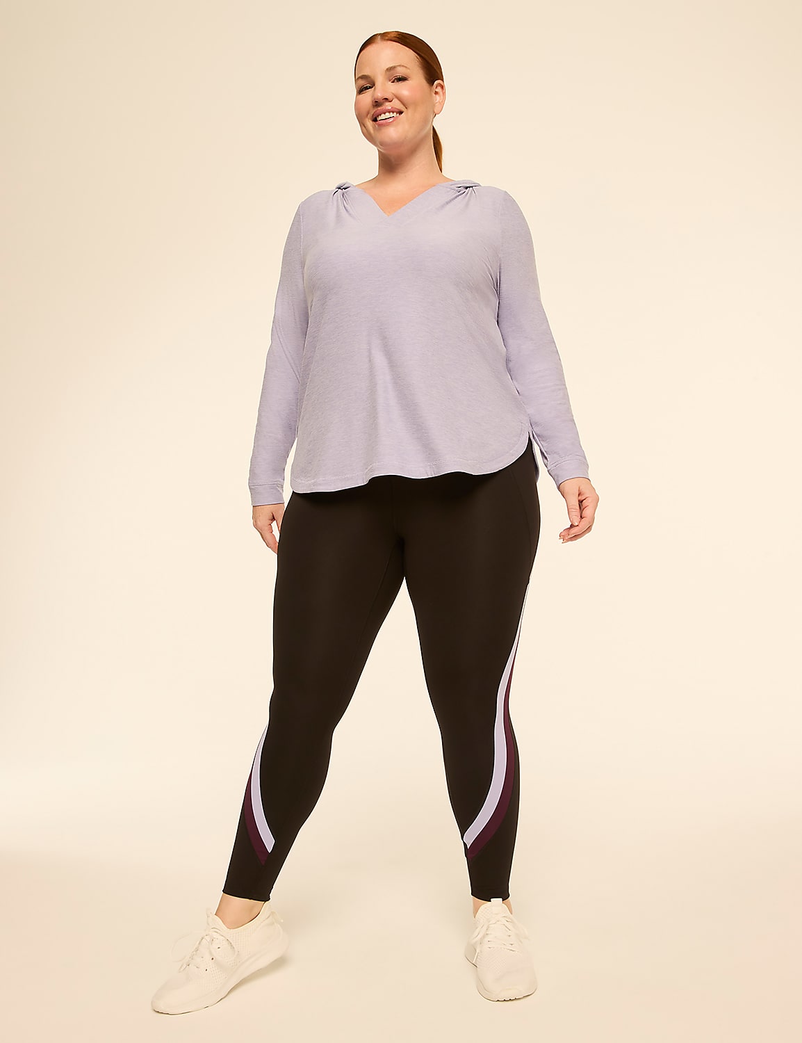 A smiling woman in a light purple hoodie and black leggings with colored stripes stands against a plain, light-colored background. Product Image 3