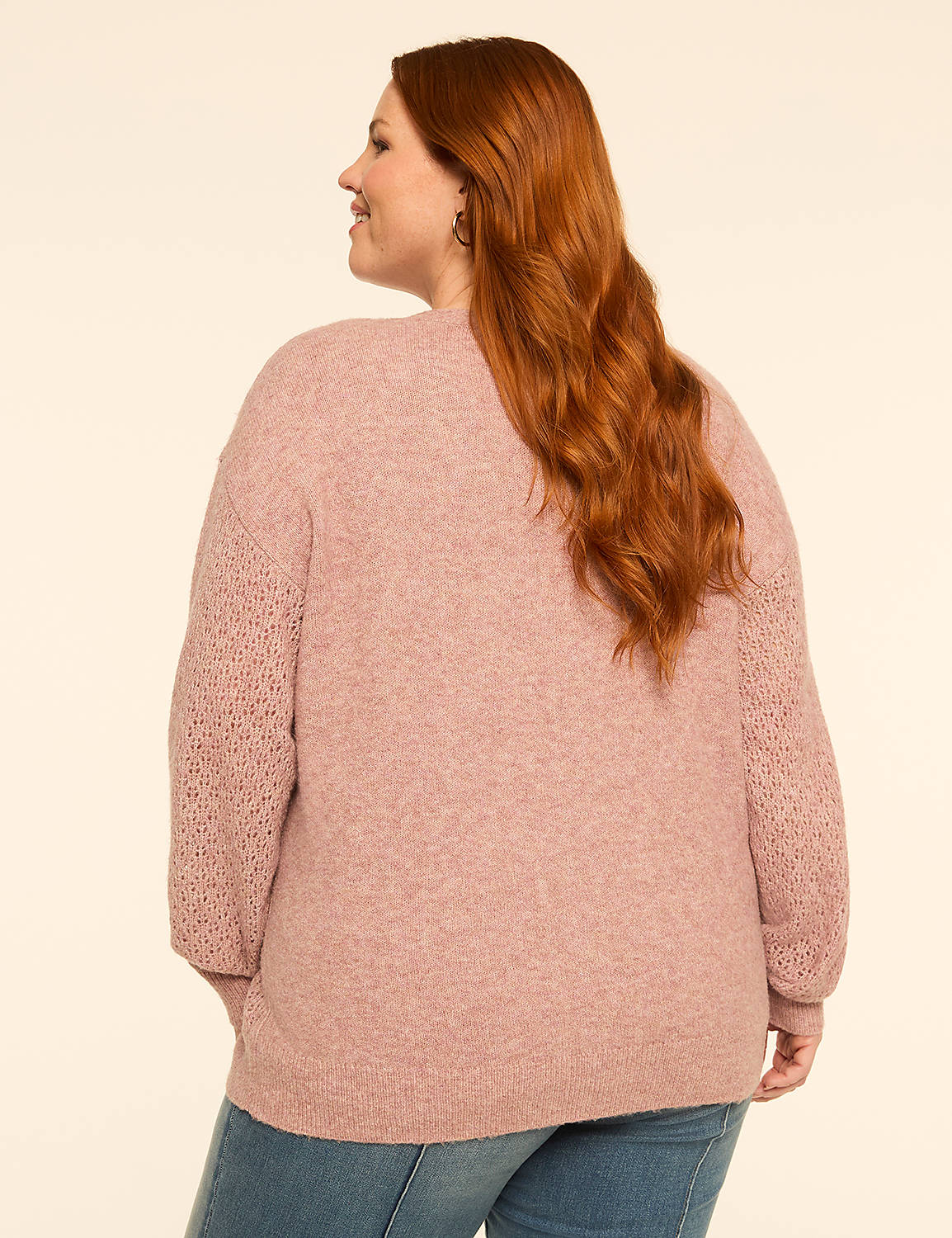 A woman with long red hair wearing a pink cardigan and blue jeans stands against a plain cream background. Product Image 2