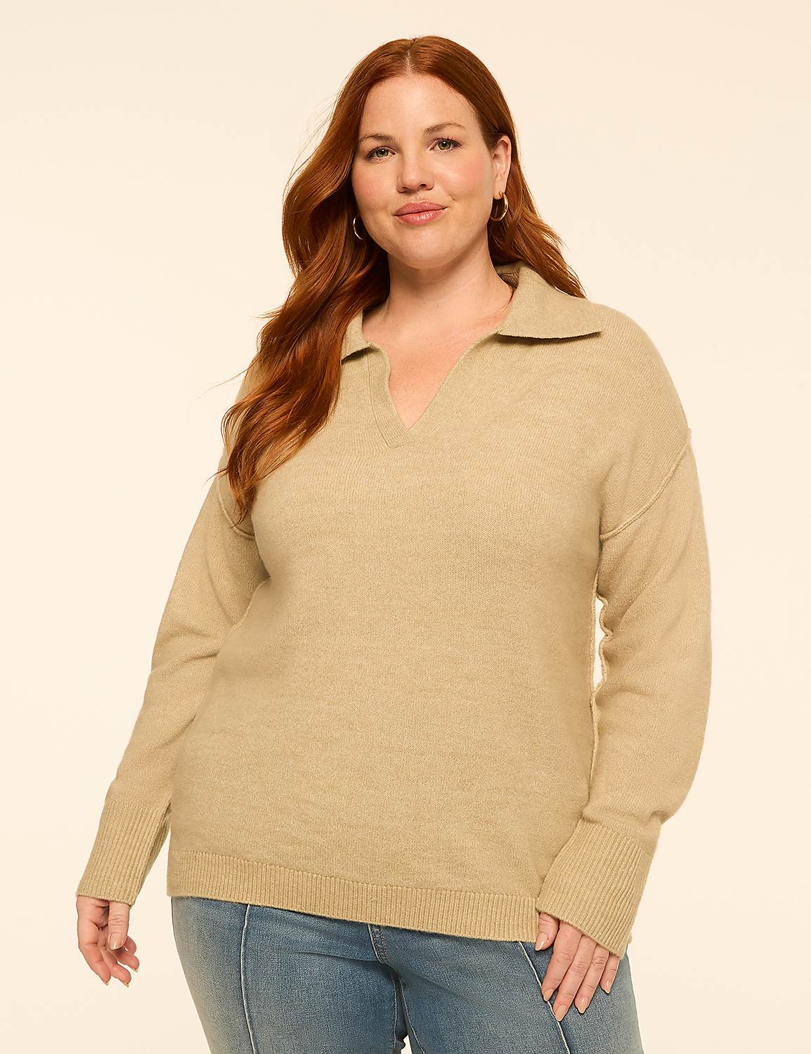 A woman with red hair and fair skin, wearing a tan collared sweater and blue jeans, stands against a plain, light-colored background. Product Image 1