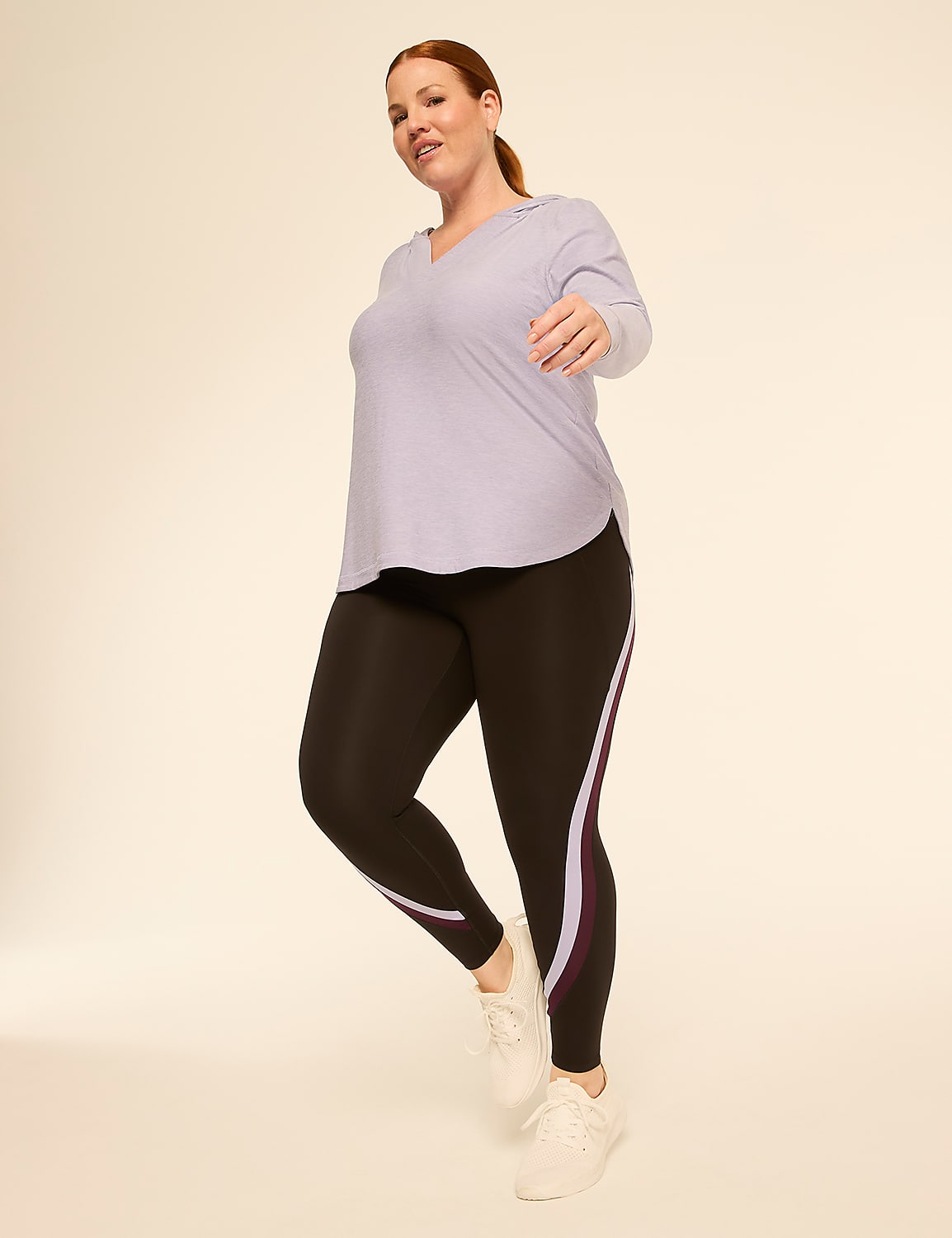 A woman in a light purple top and black leggings with colored stripes stands against a plain, light-colored background. Product Image 3