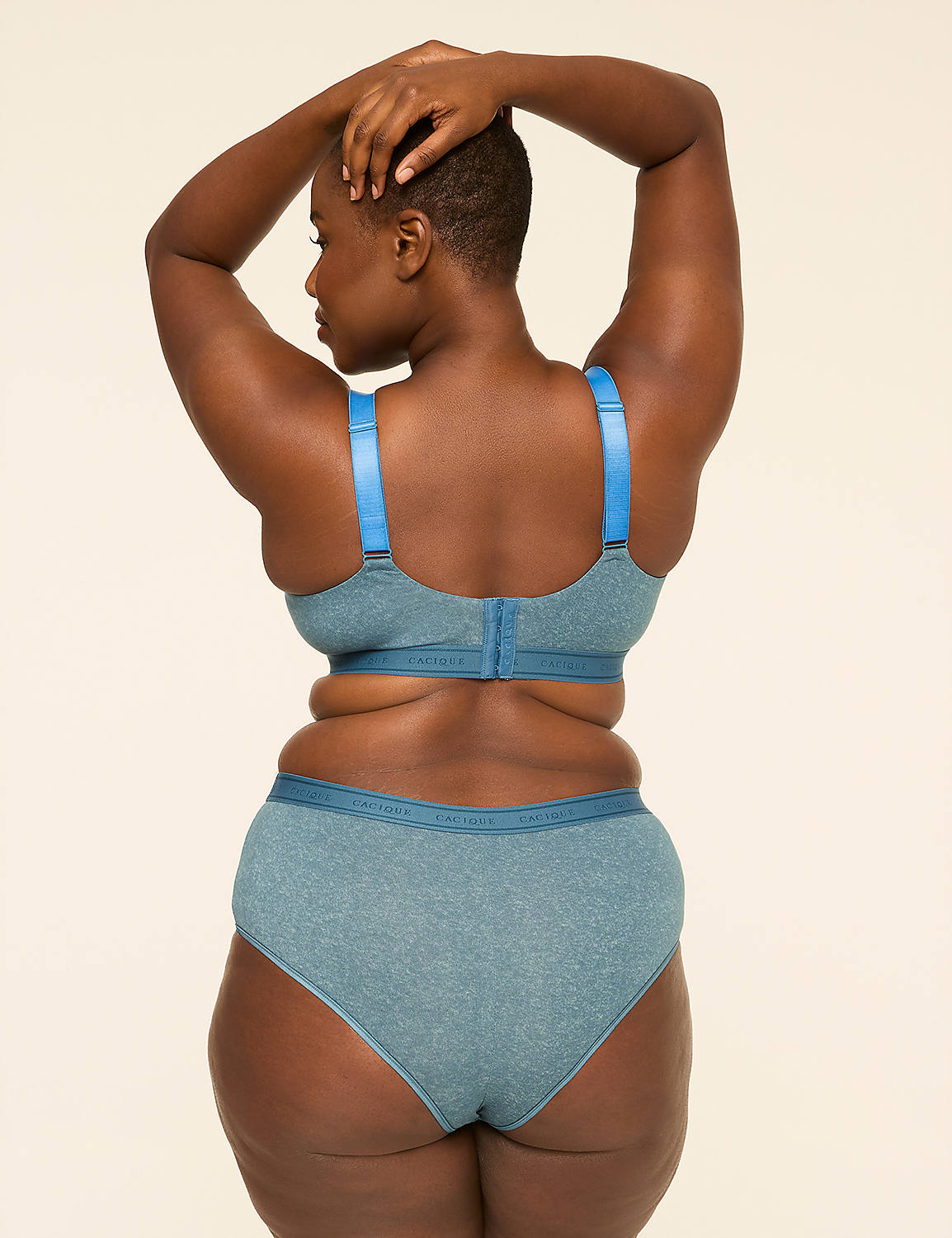 A woman in a blue bra and underwear stands with her back to the camera, hands behind her head, against a plain, light-colored background. Product Image 2