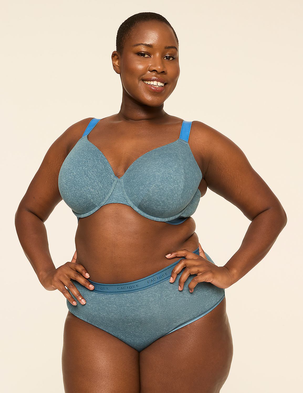 A smiling woman with dark skin and short hair poses in a blue bra and matching underwear against a plain, light-colored background. Product Image 4