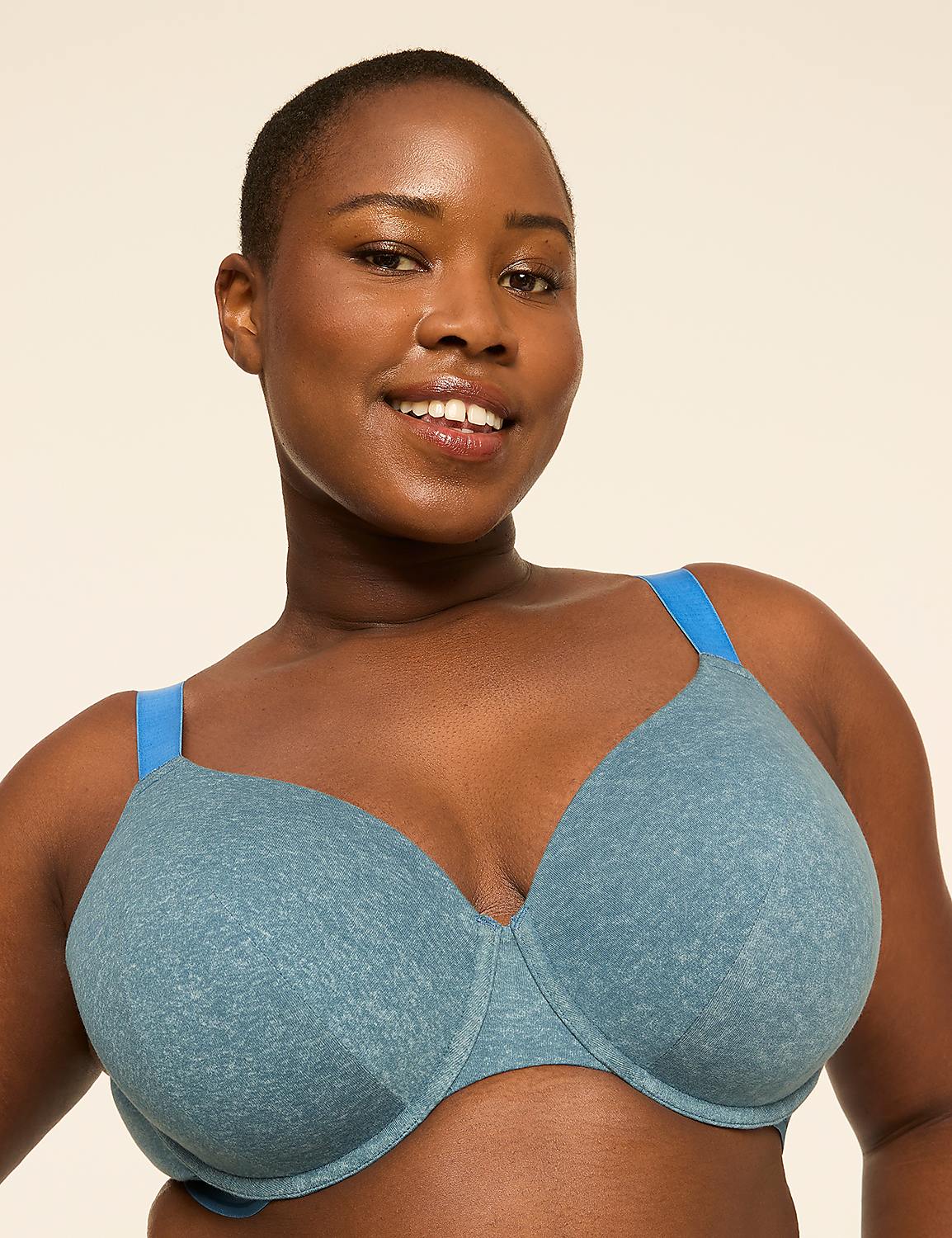A smiling woman with short hair wears a blue bra in the foreground against a plain, light-colored background. Product Image 1