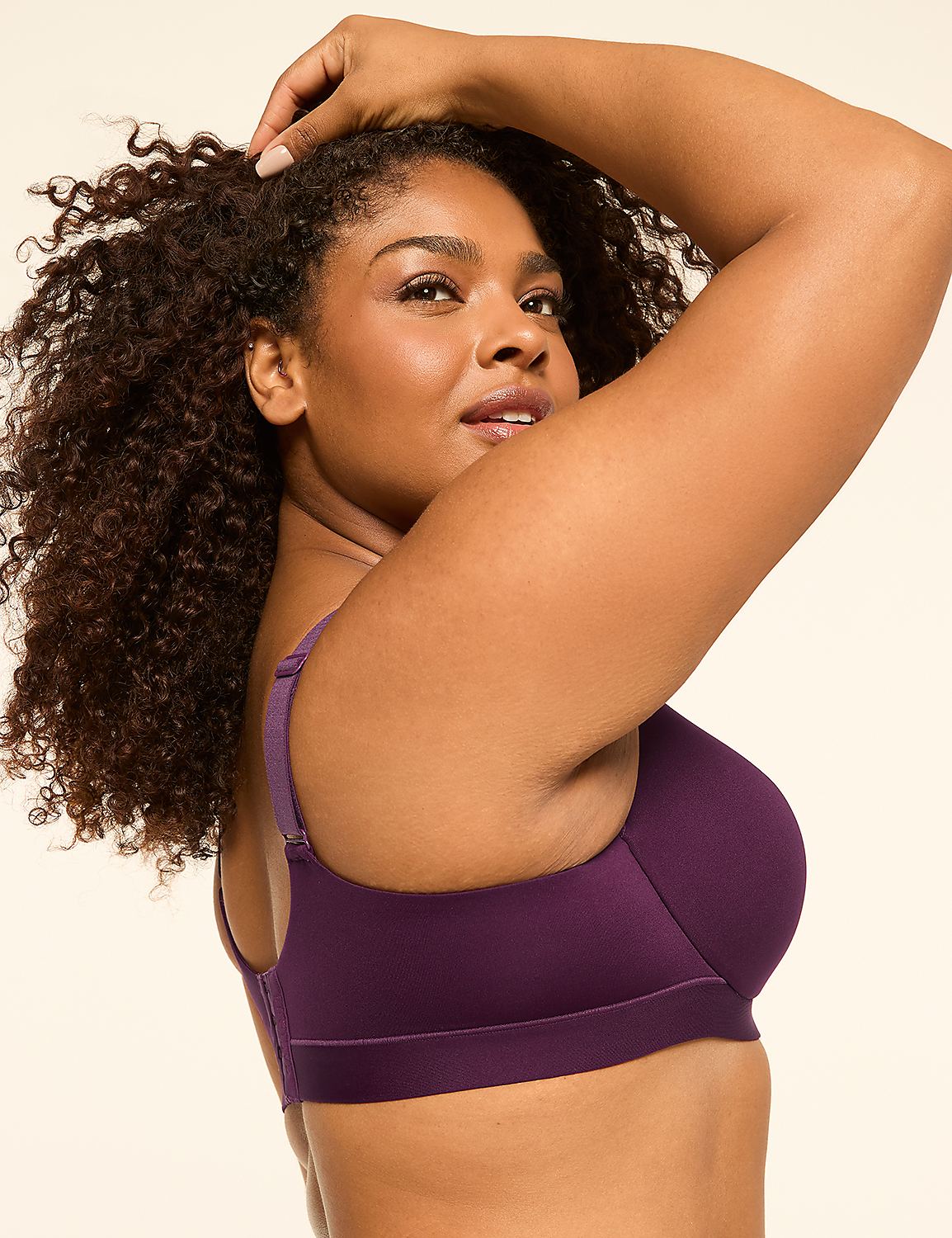A woman with curly dark hair in the foreground wears a purple bra, while the background is a plain, light-colored studio backdrop. Product Image 3