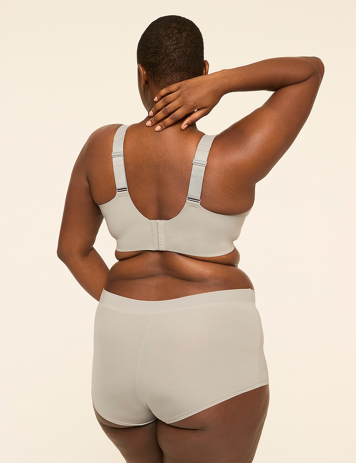 A woman in a light gray bra and underwear stands with her back to the camera, her hand touching her neck, against a plain, light background. Product Image 2