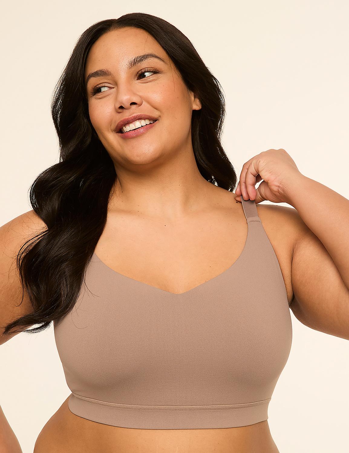 A smiling woman with dark hair wears a beige bra in the foreground against a plain, light brown background. Product Image 1