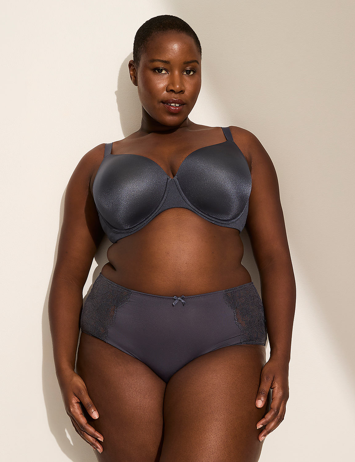 A woman in a grey bra and underwear stands against a plain, light-colored wall with a shadow cast on it. Product Image 4
