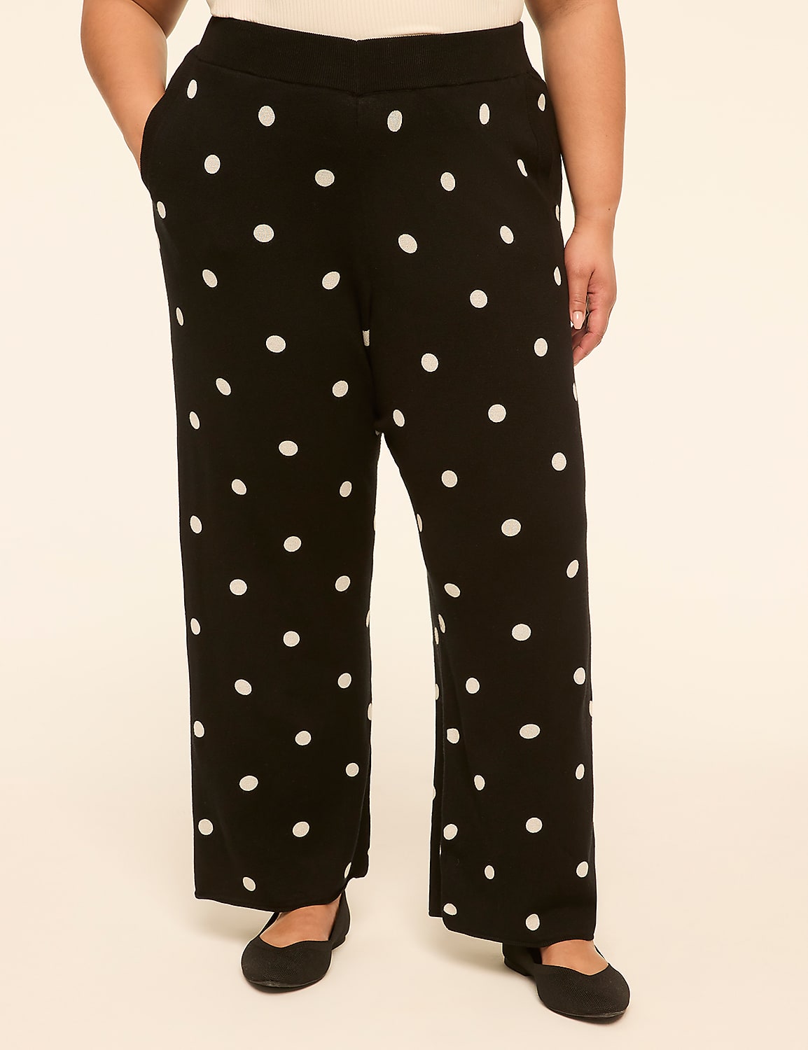 A person stands in black polka dot pants and black flats against a plain, light-colored background. Product Image 1