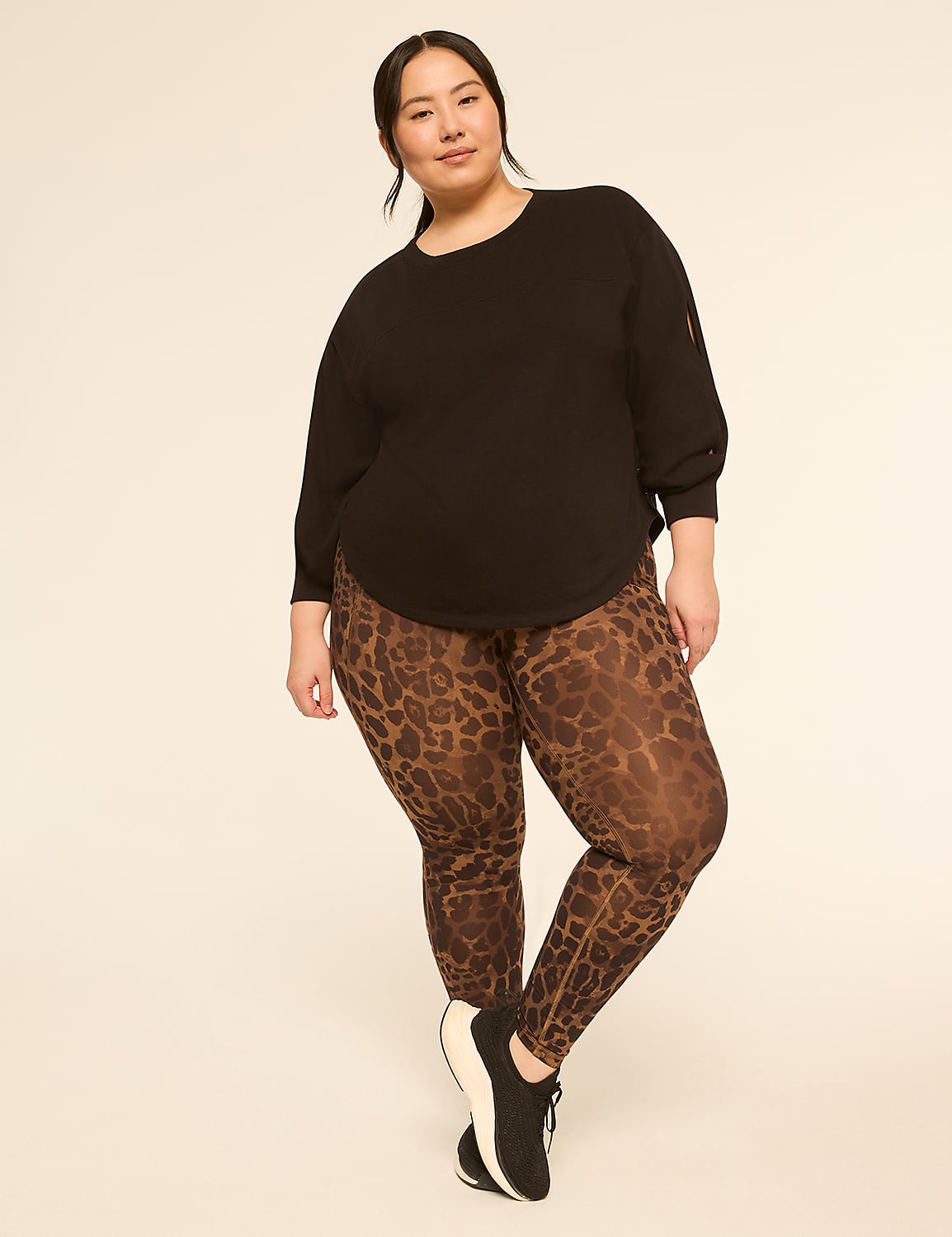 A woman in a black top and leopard print leggings stands against a plain, light-colored background. Product Image 3