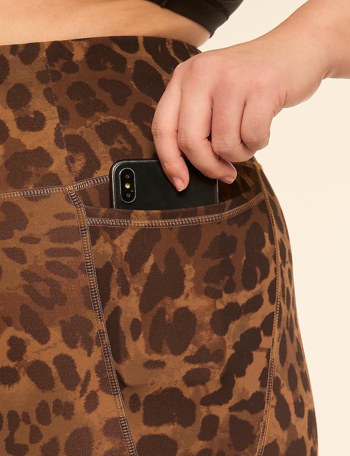 A hand places a smartphone into the pocket of leopard-print leggings against a plain, light background. Product Image 4