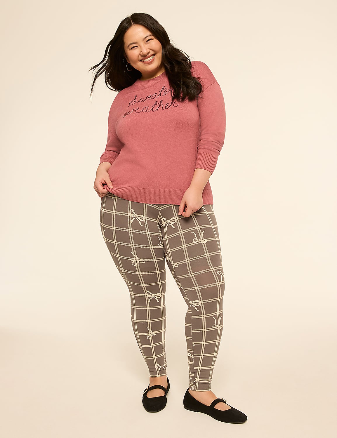 A smiling woman in a pink sweater and plaid leggings stands against a plain, light-colored background. Product Image 3