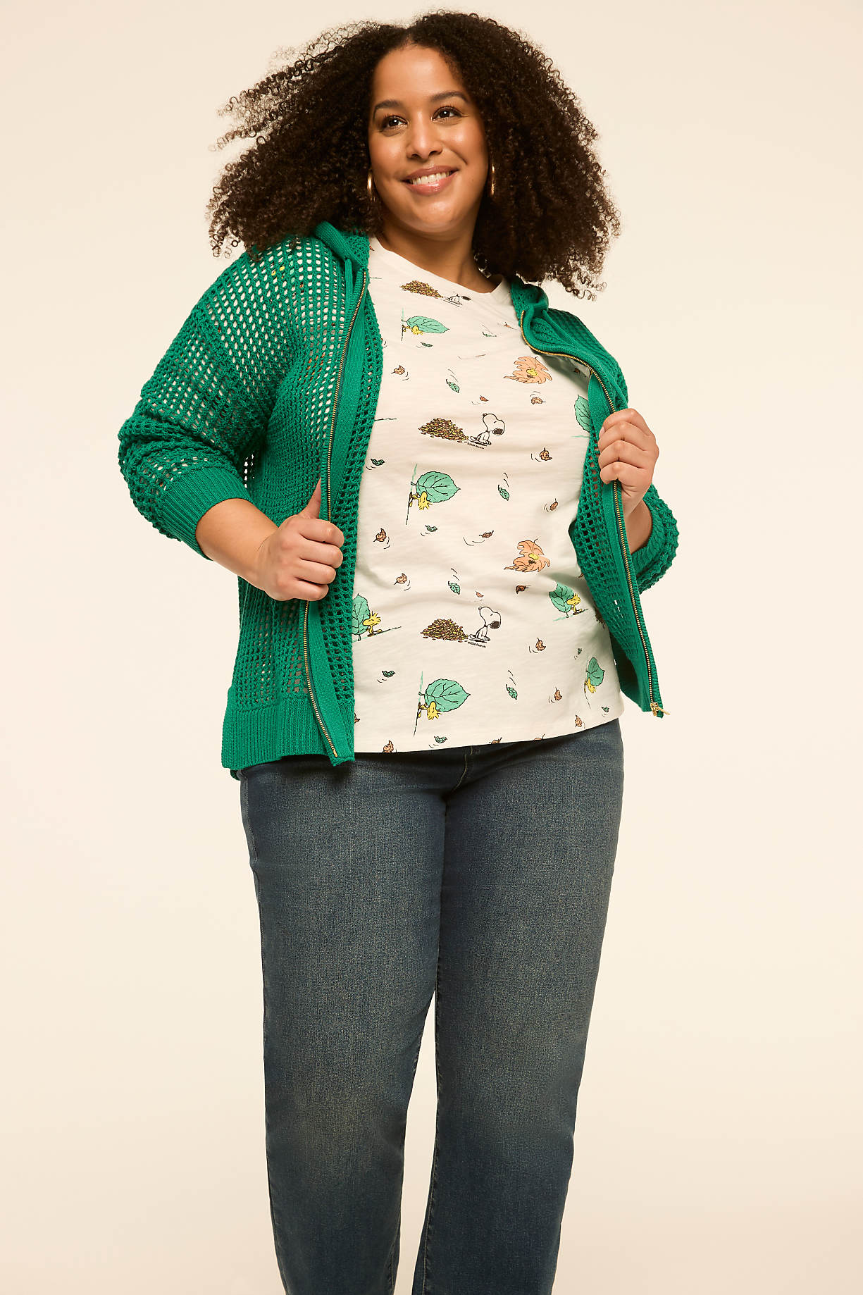 A smiling woman in a green hooded cardigan and a t-shirt with a cartoon print stands against a plain, light-colored background. Product Image 8