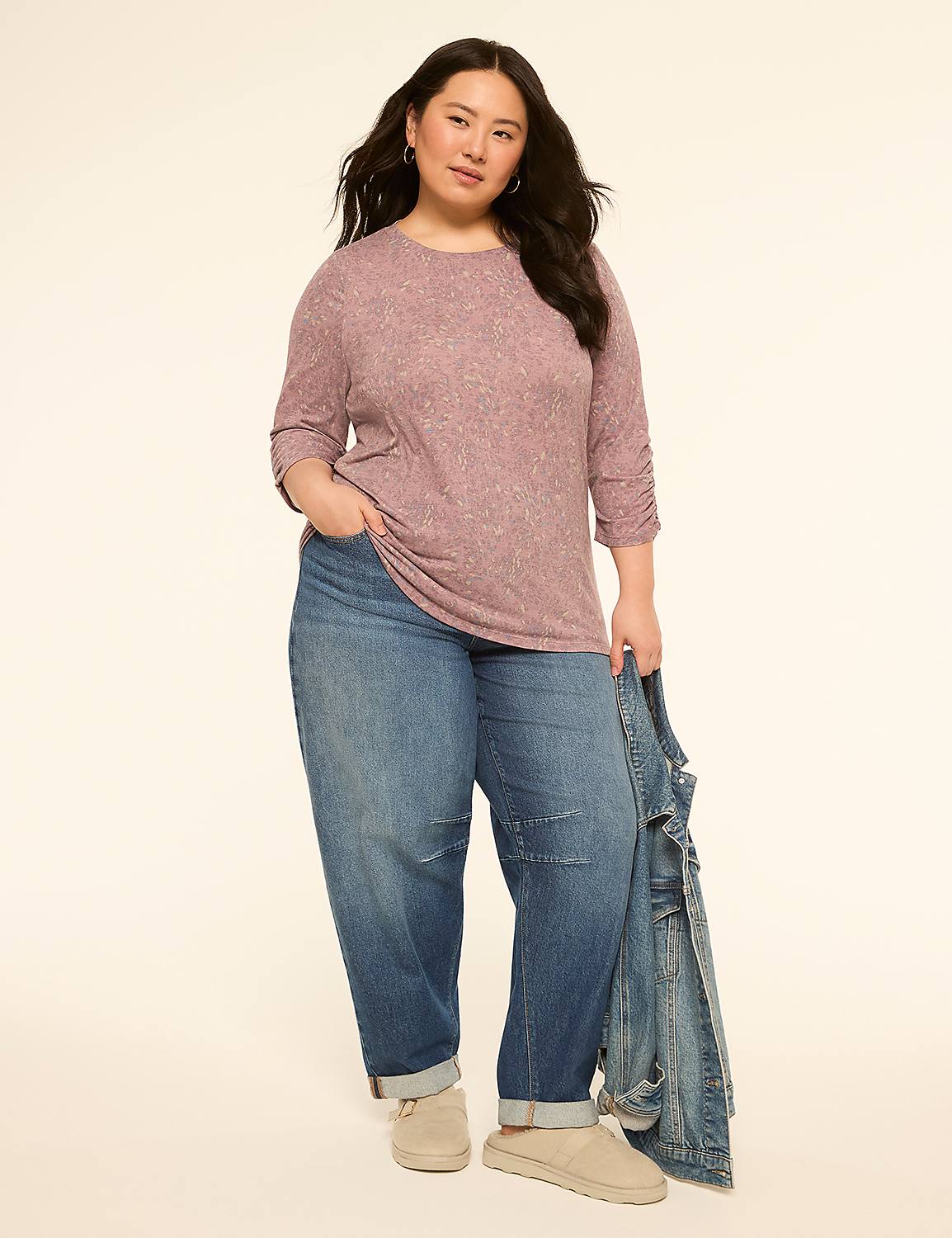 A woman in a pink top and jeans stands against a plain, light background, holding a denim jacket. Product Image 3