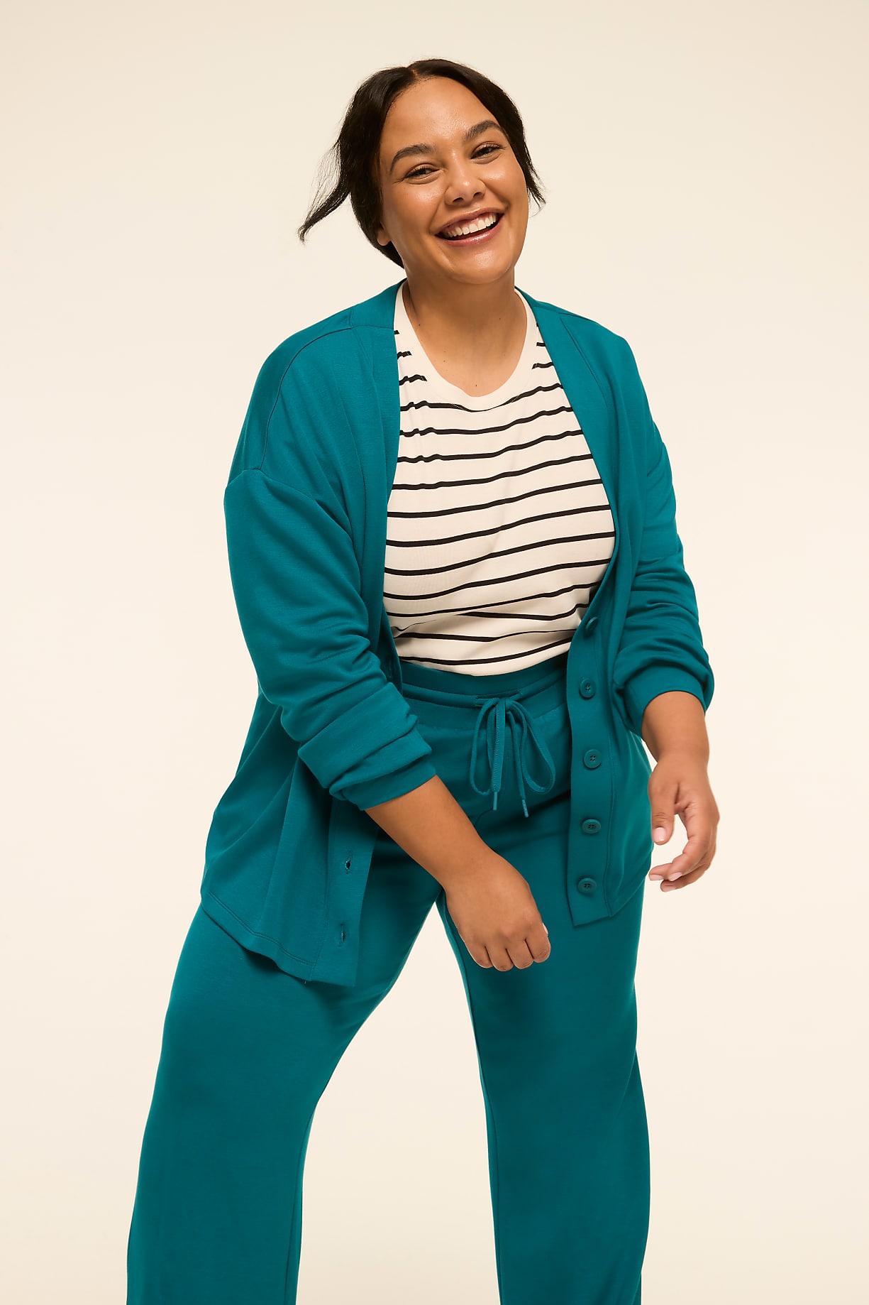 A smiling woman in a teal cardigan and matching pants stands against a plain, light-colored background. Product Image 4