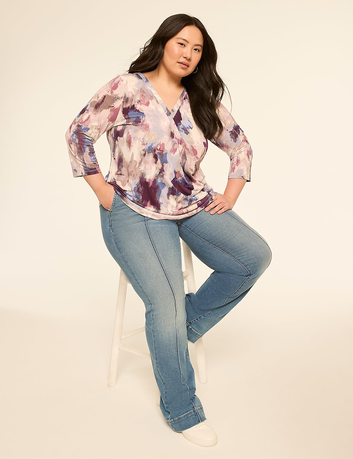 A woman with dark hair and a floral top sits on a stool in front of a plain, light-colored background. Product Image 4
