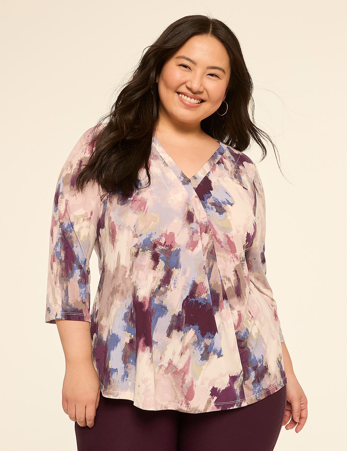 A smiling woman with dark hair wears a colorful, abstract-print blouse and dark pants against a plain, light-colored background. Product Image 1