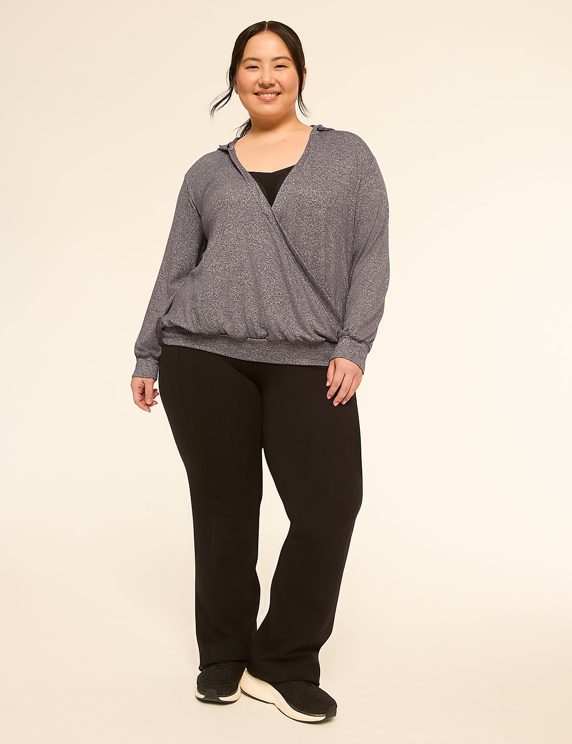 A smiling woman in a gray wrap top and black pants stands against a plain, light-colored background. Product Image 3
