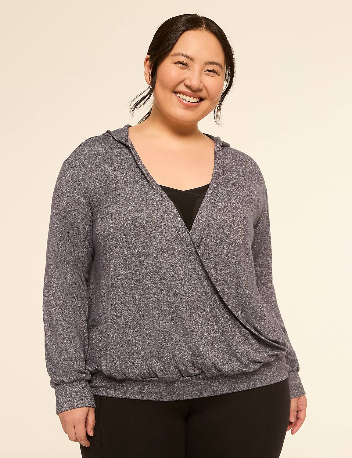 A smiling woman in a grey wrap-style hoodie stands against a plain, light-colored background. Product Image 1