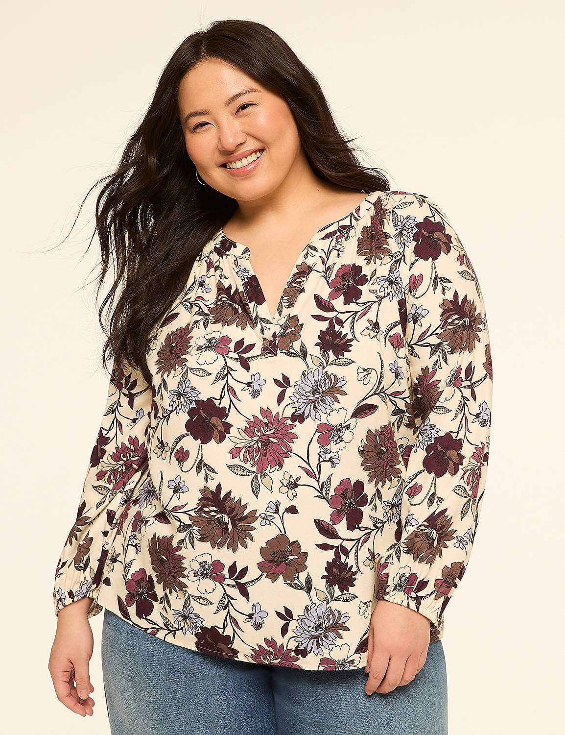 A smiling woman in a floral blouse stands against a plain, light-colored background. Product Image 1