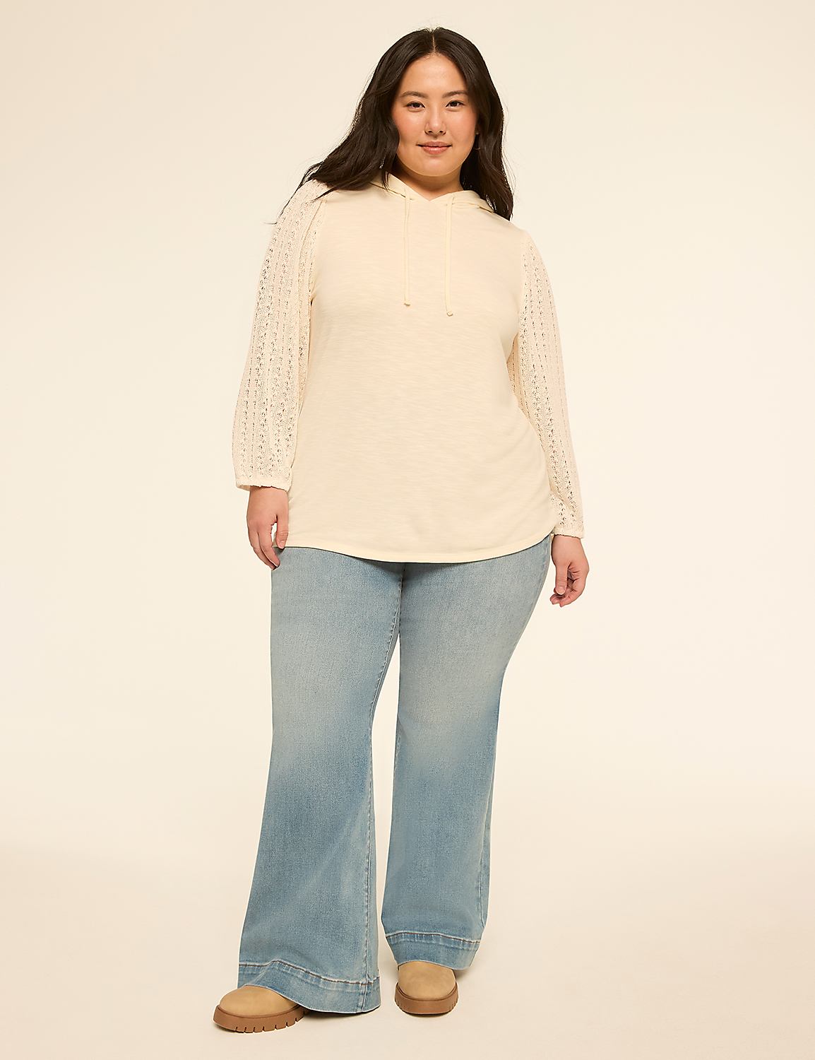 A woman in a cream-colored hoodie and light-wash flared jeans stands against a plain, light-colored background. Product Image 3