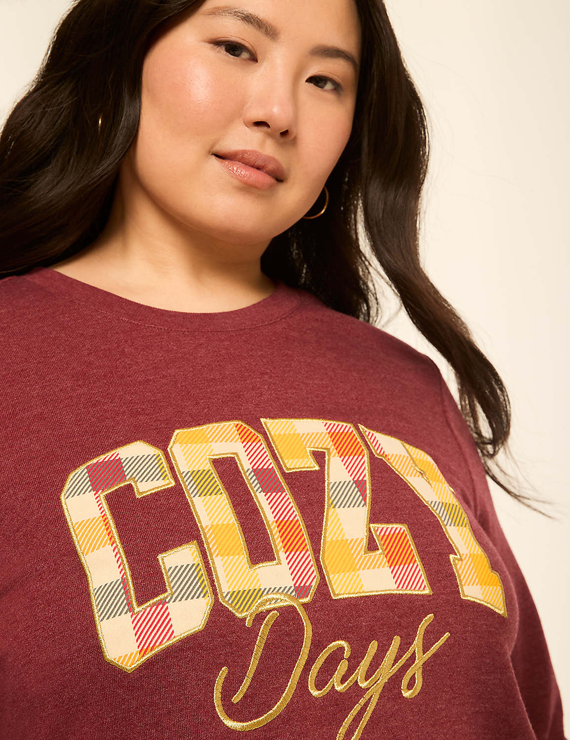 A woman in a maroon sweatshirt with "Cozy Days" emblazoned on it is shown against a plain, light background. Product Image 4