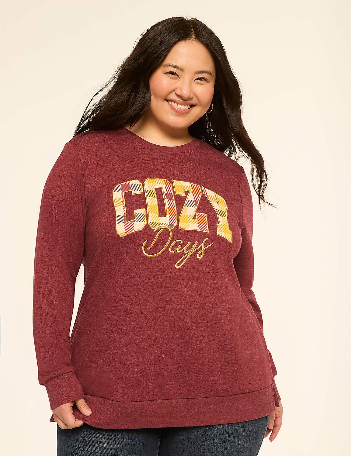 A smiling woman in a maroon sweatshirt with "Cozy Days" printed on it stands against a plain, light background. Product Image 1