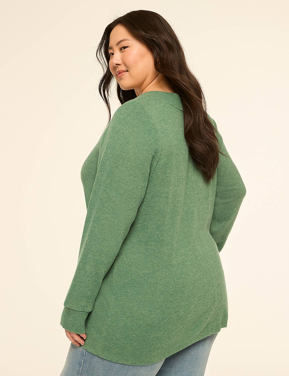A woman in a green sweater and jeans stands against a plain, light-colored background. Product Image 2