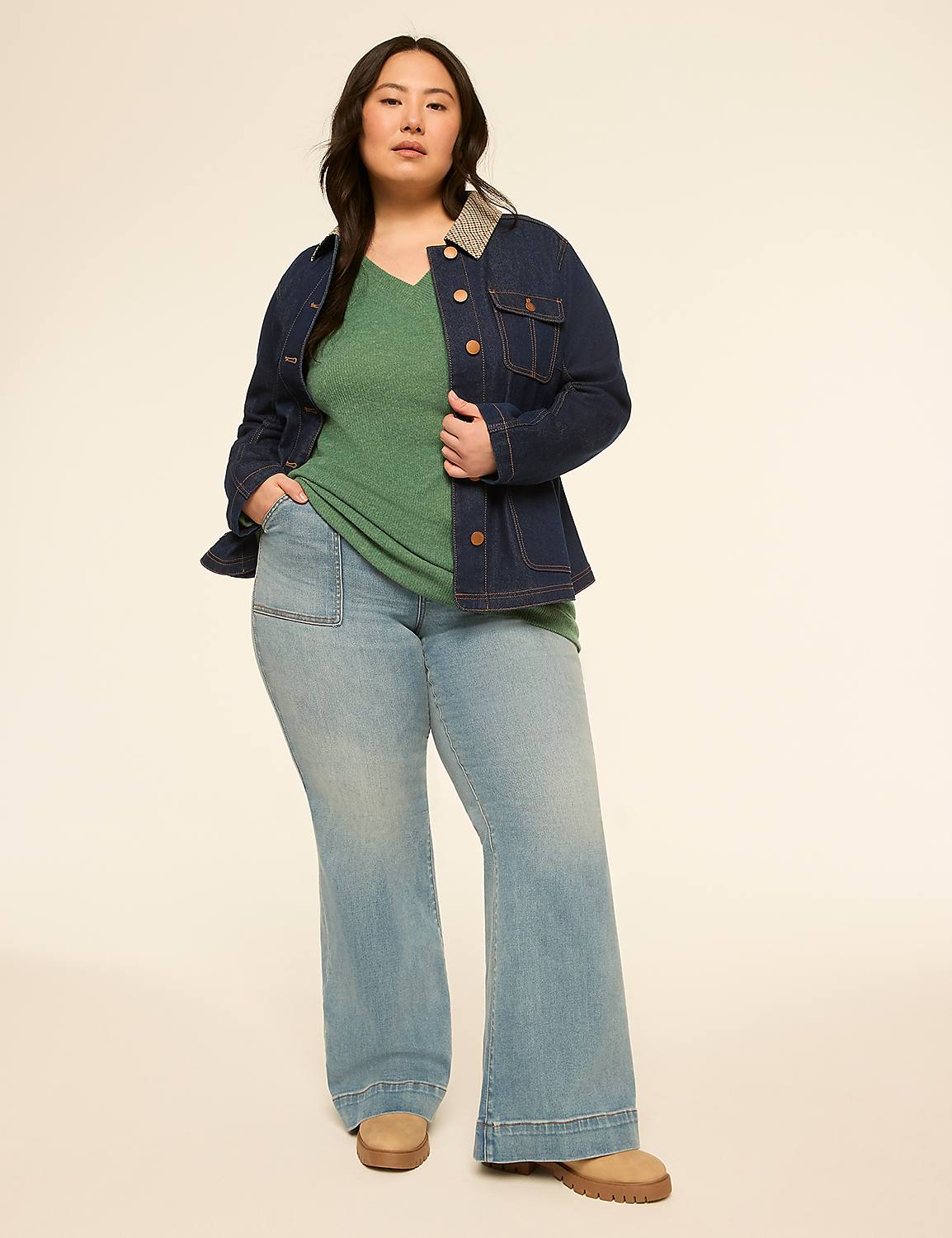A woman in a green top, denim jacket, and light wash flared jeans stands against a plain, light-colored background. Product Image 3