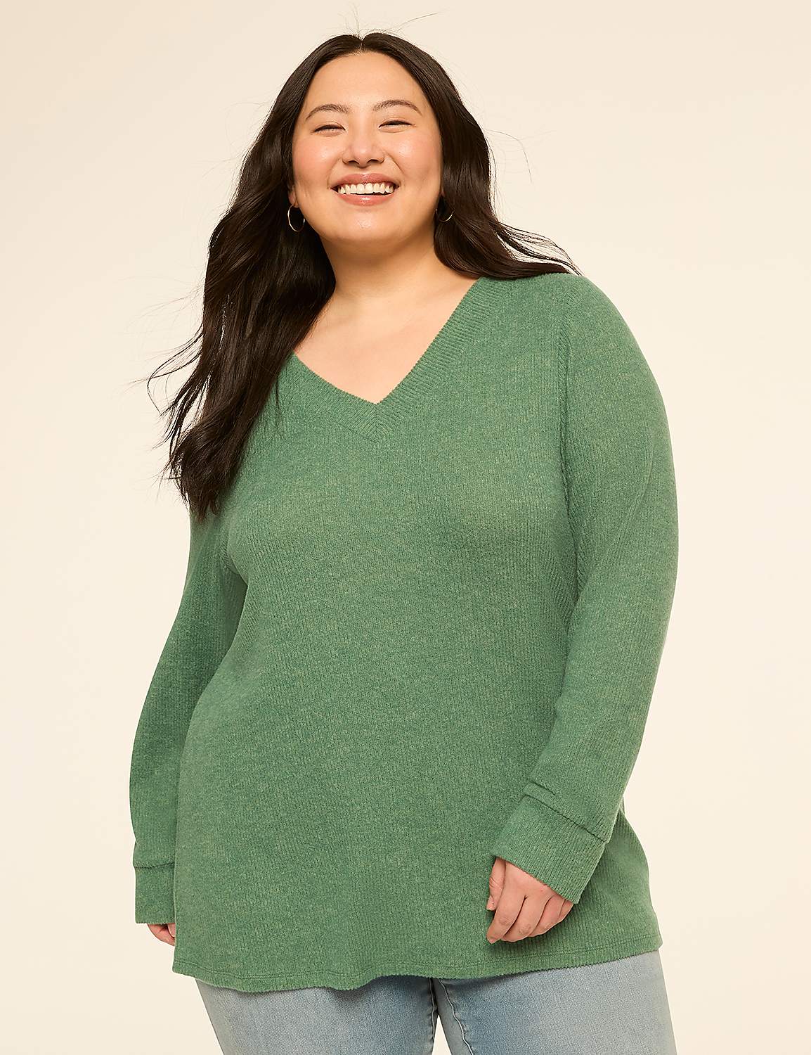 A smiling woman in a green v-neck sweater stands against a plain, light-colored background. Product Image 1