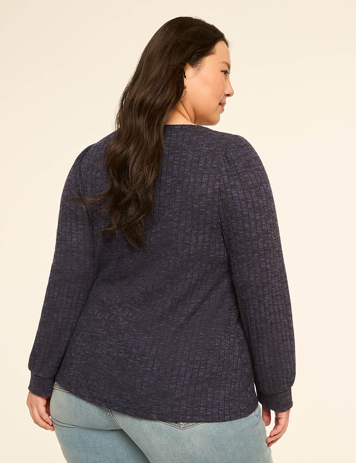 A woman in a dark blue textured top and light blue jeans stands against a plain, light-colored background. Product Image 2