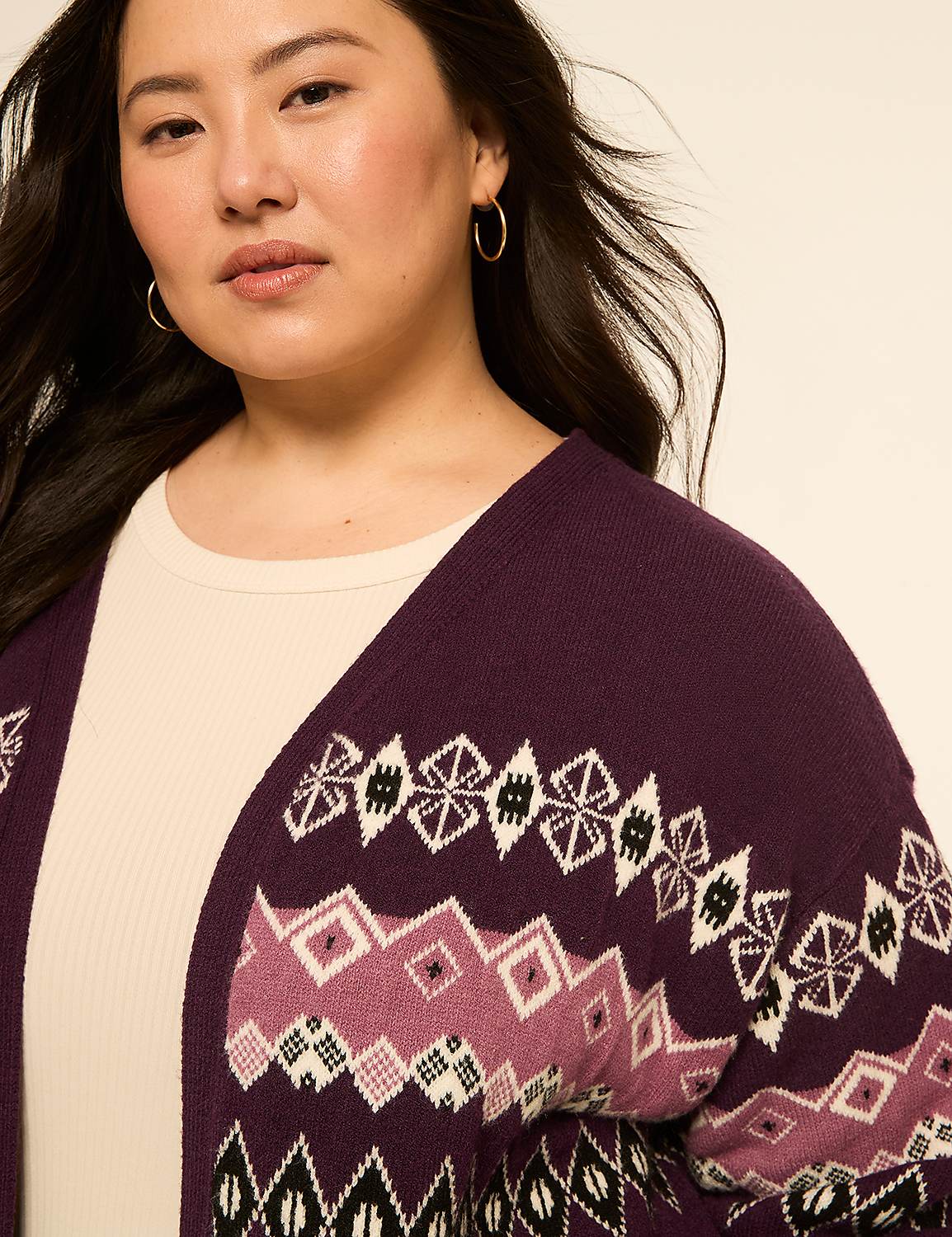 A woman with dark hair and hoop earrings wears a purple cardigan with a geometric pattern over a cream-colored top, against a plain beige background. Product Image 5