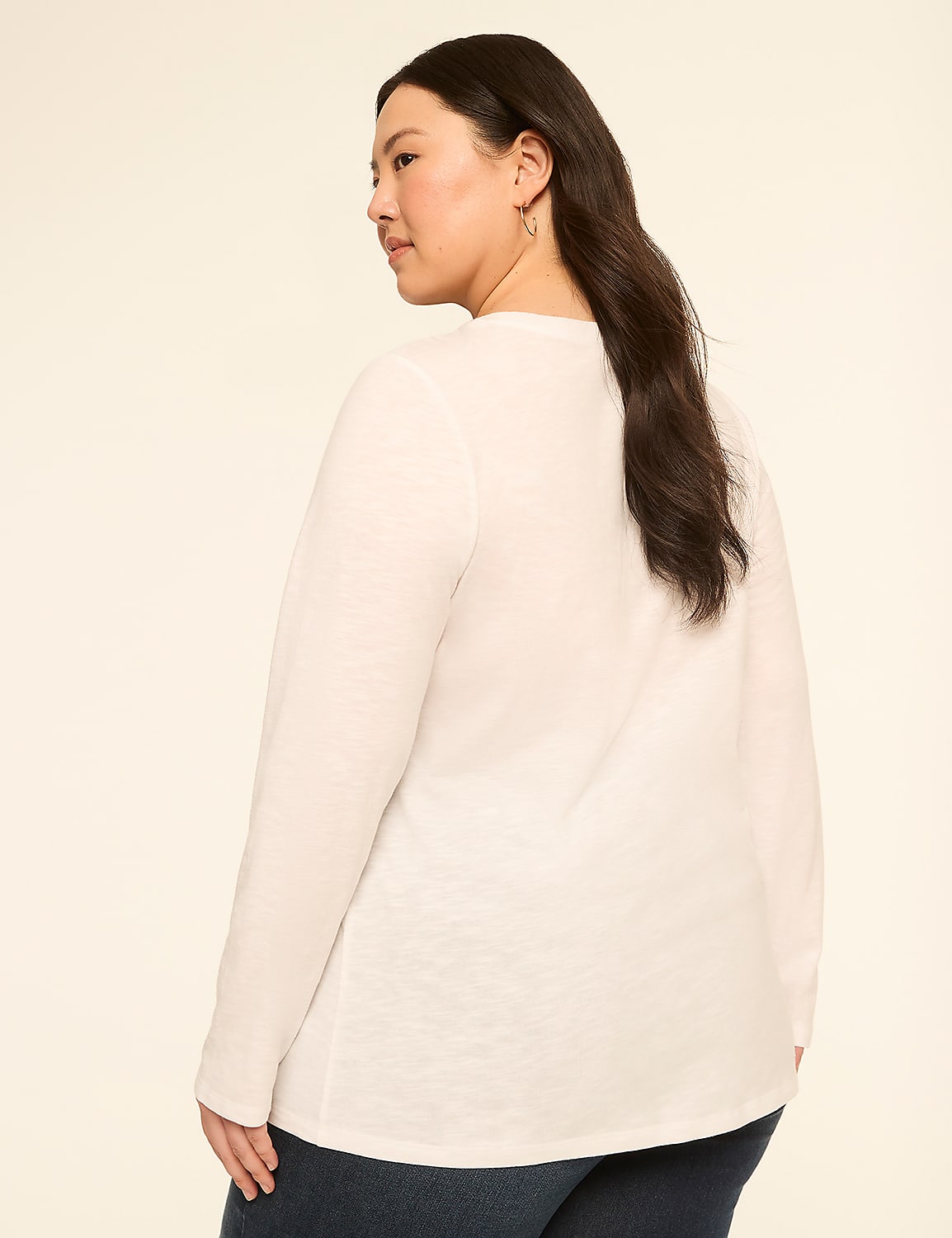 A woman in a white long-sleeved shirt and dark jeans stands against a plain, light-colored background. Product Image 2