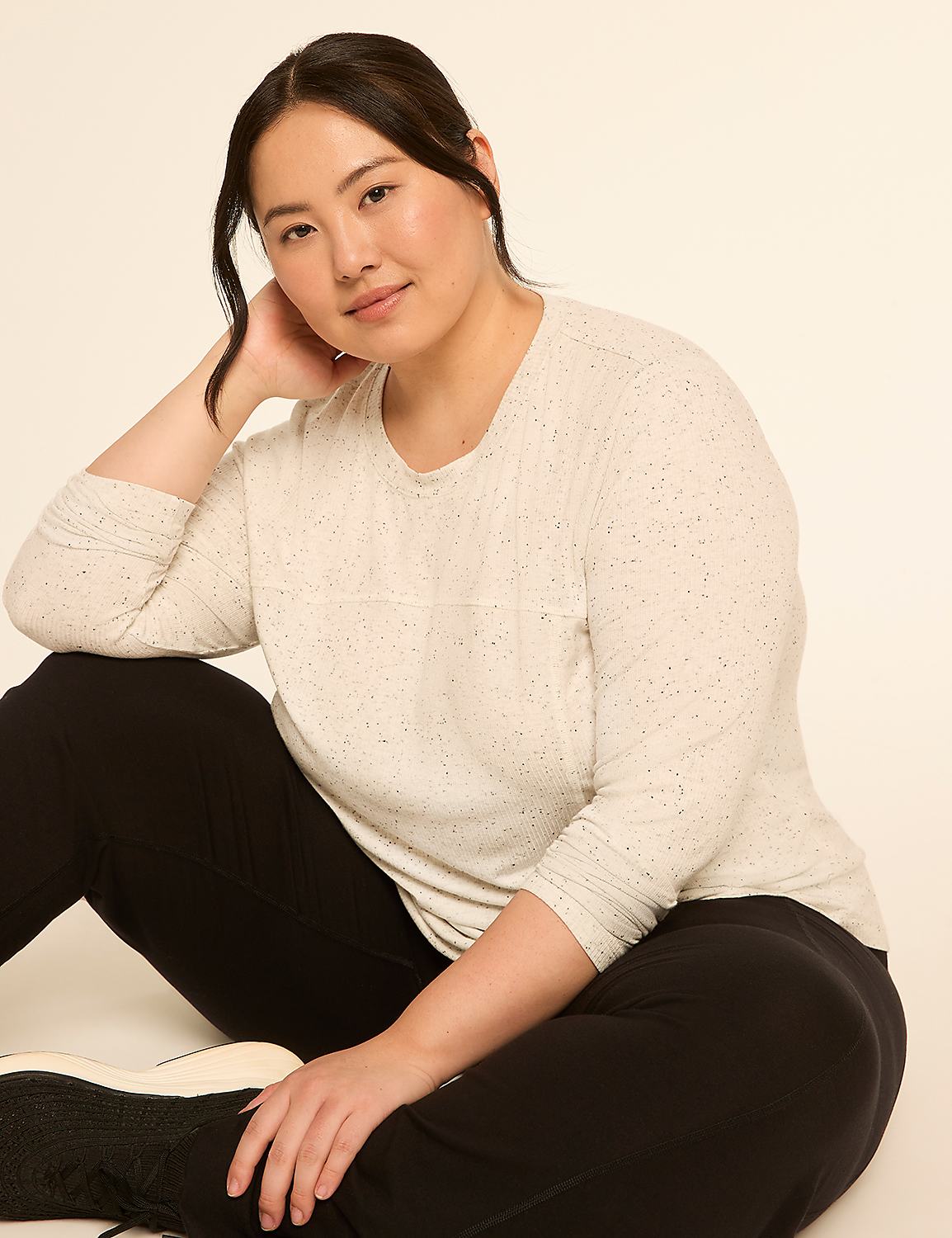 A woman in a speckled cream top and black pants poses against a plain, light background. Product Image 3