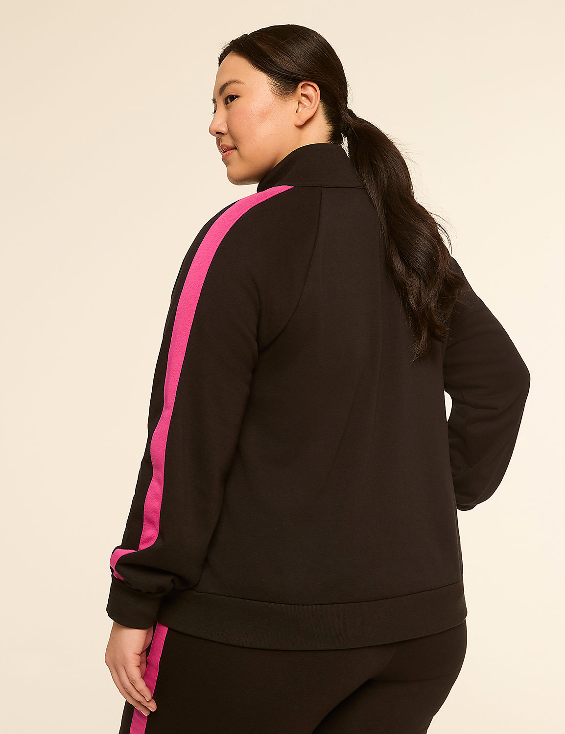 A woman in a black and pink tracksuit stands against a plain, light-colored background. Product Image 2