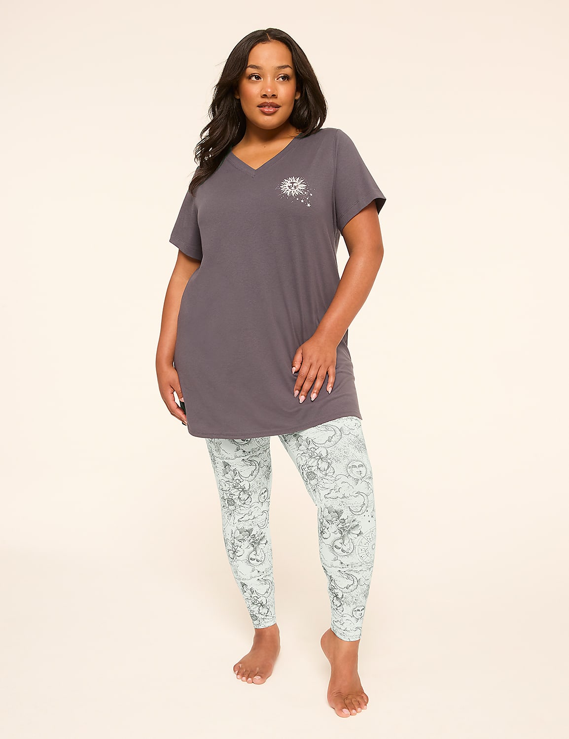 A woman stands in the foreground wearing a grey tunic and patterned leggings against a plain, light-colored background. Product Image 1