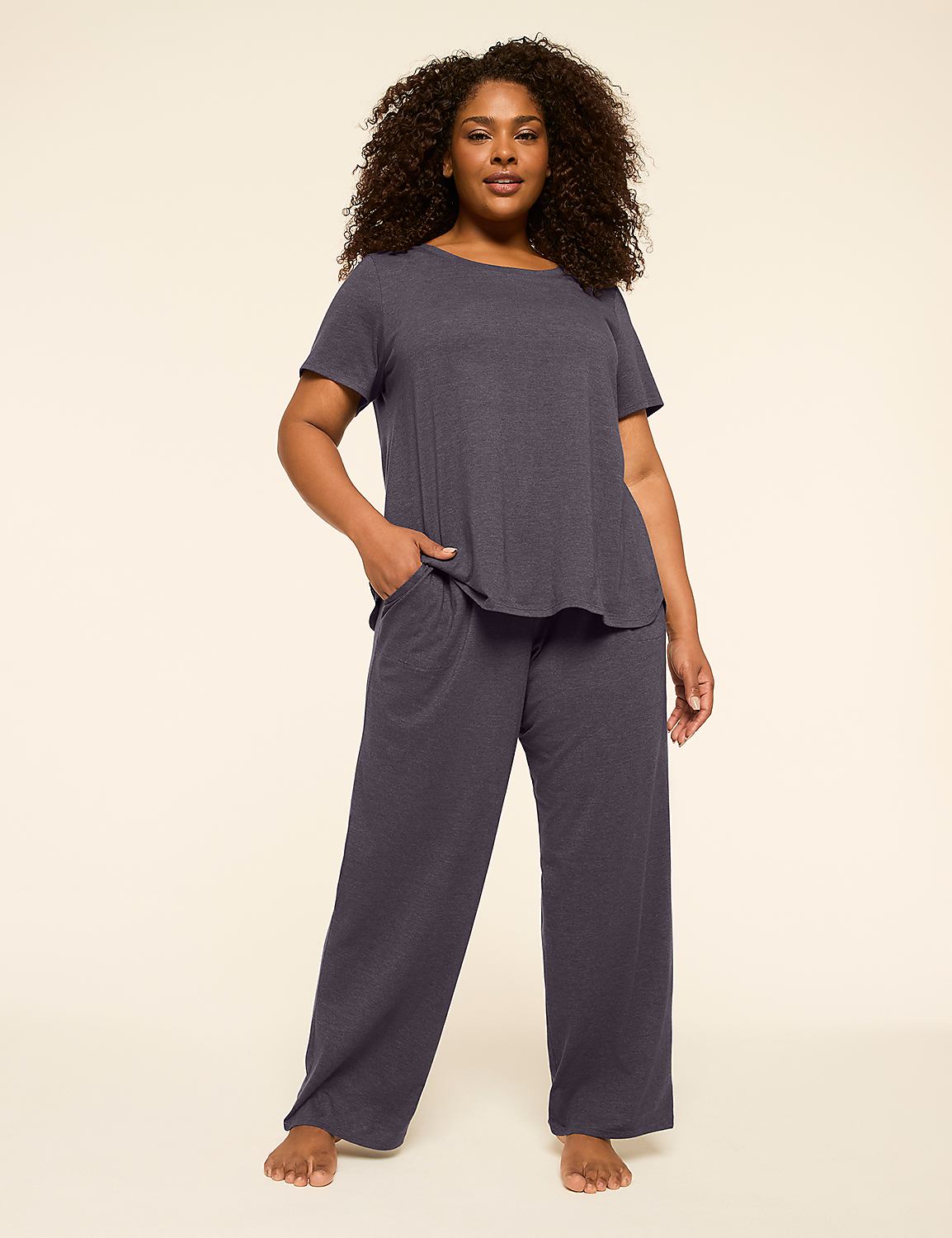 A woman in a navy blue pajama set stands against a plain, light beige background. Product Image 1