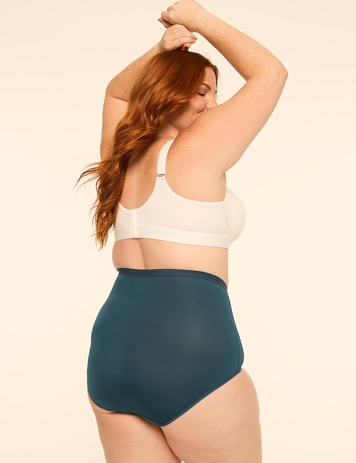 A woman with red hair in a white bra and teal underwear poses with her arms raised against a plain, light-colored background. Product Image 2