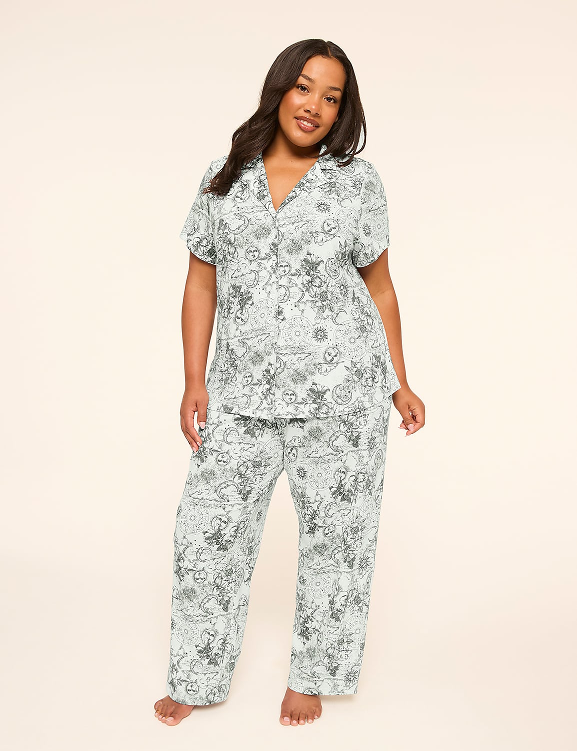 A woman stands in a light blue pajama set with a cartoon print against a plain, light background. Product Image 1