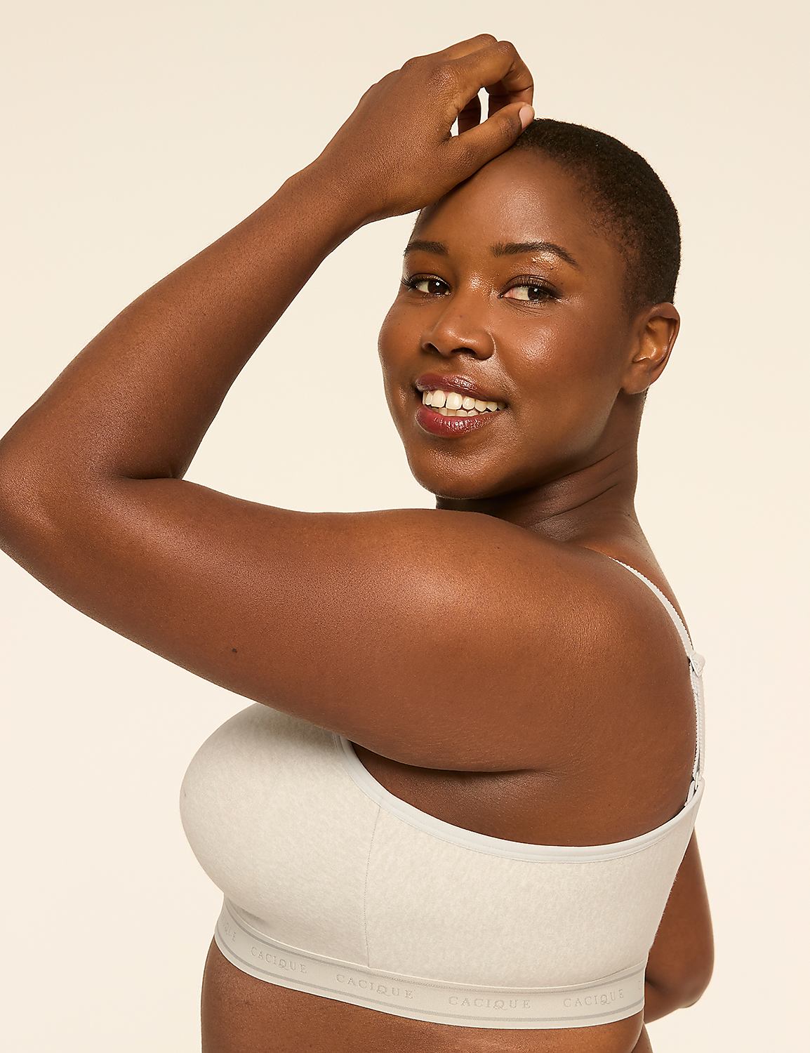 A woman with dark skin and short hair smiles as she poses with her arm raised against a plain, light-colored background. Product Image 3